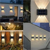 A collection of modern solar wall lights illuminating a garden or outdoor area.