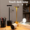 A modern touch desk lamp with a black base and a gold finish, illuminating a workspace.