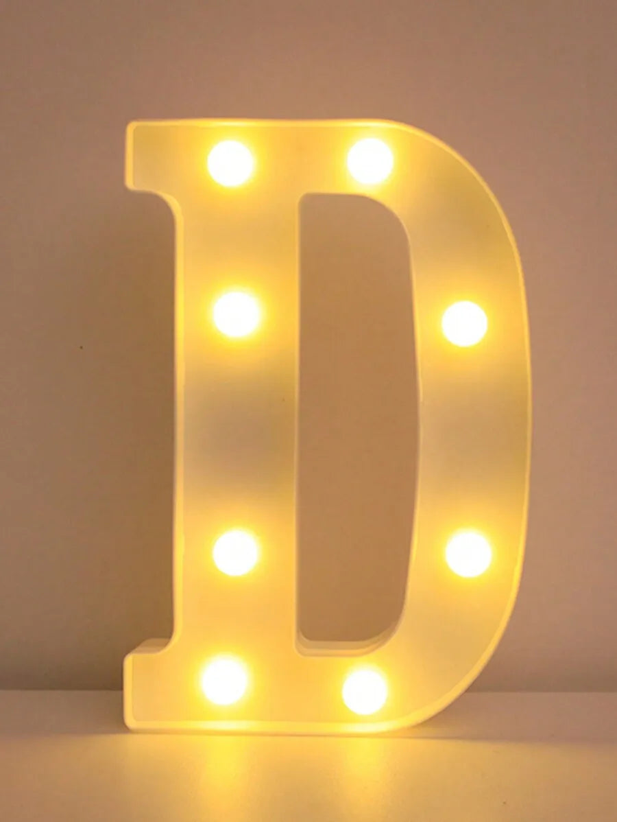 Una luz nocturna de LED amarilla brillante con la letra D iluminando un fondo oscuro.