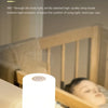 A white LED desk lamp is shown on a table, illuminating a person's face in a bedroom setting.