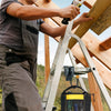 A person uses a metal tool belt hook and holster system on wooden framing materials.