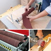 Hands are rolling aluminum oxide sandpaper onto a piece of wood for sanding or finishing work.