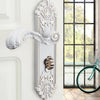A decorative silver European style door lock with an ornate handle and keyhole mounted on a white wall.