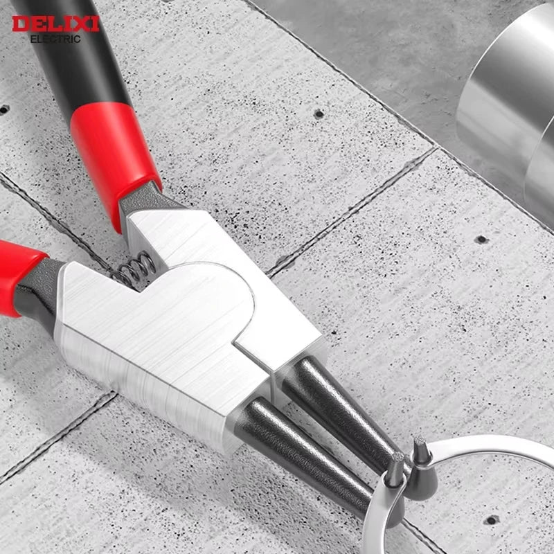 A close-up view of precision dual-purpose card spring pliers with red and silver handles resting on a metal surface.