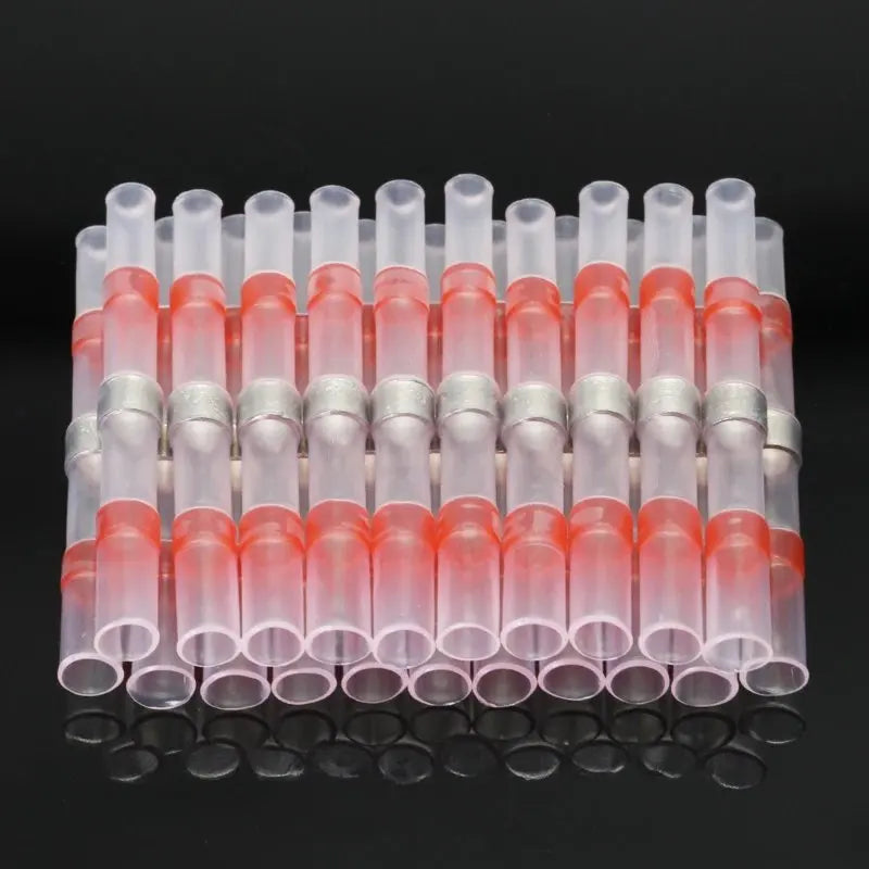 Una fila de conectores de alambre retráctil de plástico transparente con puntas rosa y blanca, dispuestos en línea.
