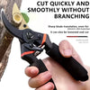 A hand holds a black and orange garden pruning shear with a sharp blade, demonstrating its use for cutting branches.