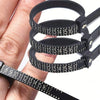 A hand holds a black accurate finger ring sizer with multiple rings for measuring fingers.