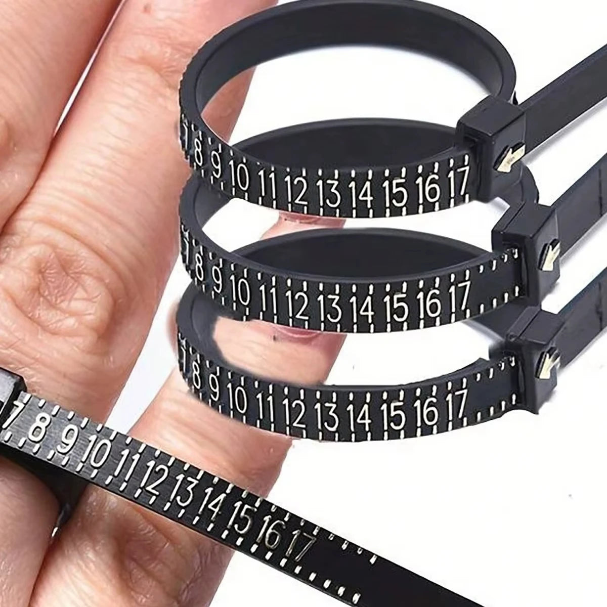 A hand holds a black accurate finger ring sizer with multiple rings for measuring fingers.