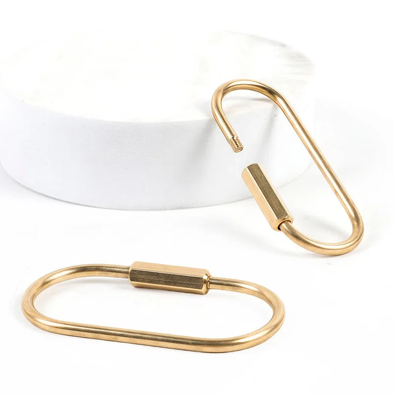 Gold-Messing-Schlüsselring-Karabinerclip auf weißer Oberfläche.