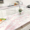 A kitchen countertop featuring glossy pink marble contact paper used for cabinet fronts and a large prep surface.