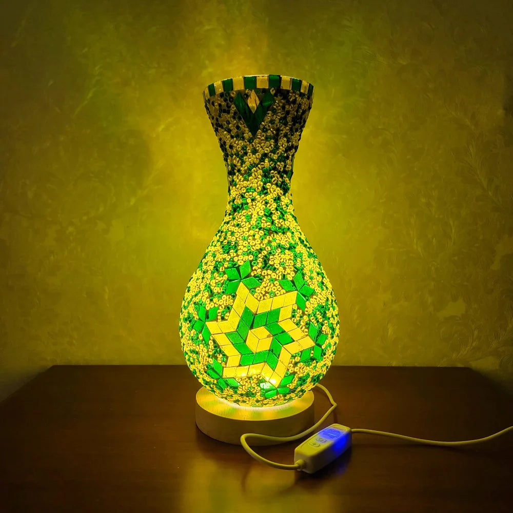 Lámpara de mesa de vidrio con incrustación verde y diseño de estrella sobre una superficie de madera.