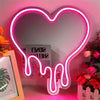 Herzförmiges Neon-Schild mit rosa Leuchten und Tropfeffekt an der Wand.
