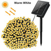A cluster of warm white solar powered outdoor LED string lights with a black mounting pole.
