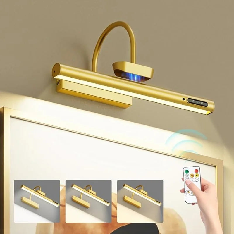 A gold wall mounted LED picture light fixture with a flexible arm and remote control is shown above a framed picture.