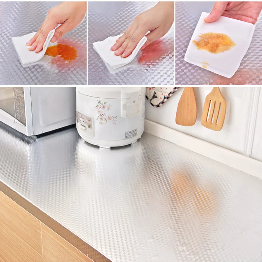 Hände wischen orange und rote Flecken von Aluminiumfolien-Wandstickern auf einer Küchenarbeitsplatte ab.
