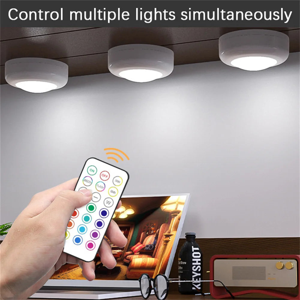 Une main tient une télécommande sans fil pour contrôler plusieurs lumières, démontrant la fonctionnalité RGB sous le meuble