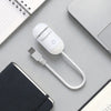 A white 2-in-1 Galaxy Star Projector night light with a cord rests on a gray surface next to a notebook and a spiral-bound pa