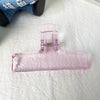 Klares Acryl-Federclip mit rosa Tönung auf weißem Untergrund