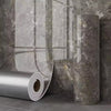 Rouleau d'autocollants muraux imitation marbre adhésifs sur un mur gris texturé.