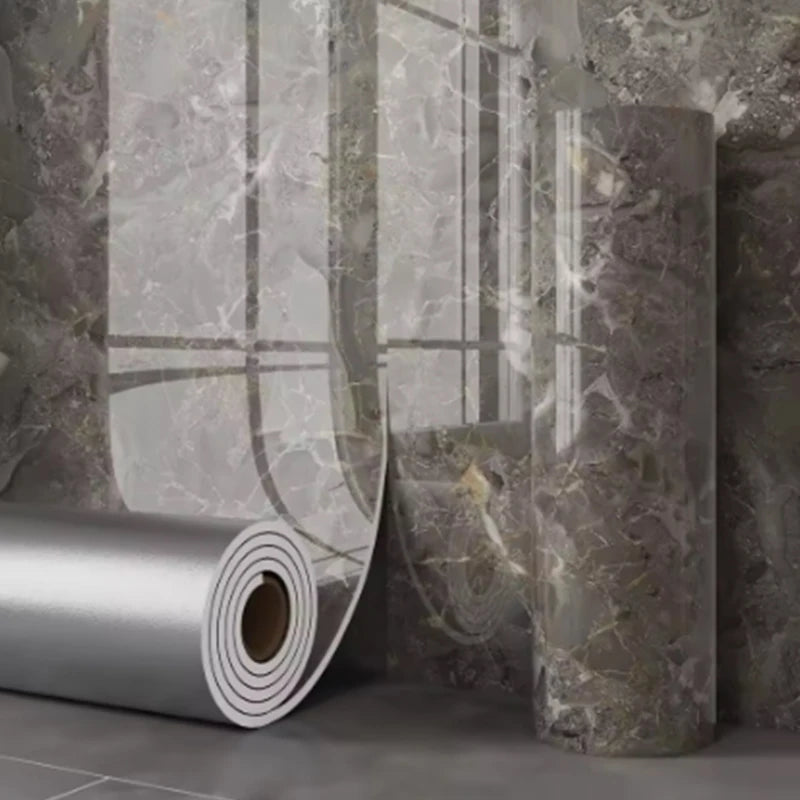 Rouleau d'autocollants muraux imitation marbre adhésifs sur un mur gris texturé.