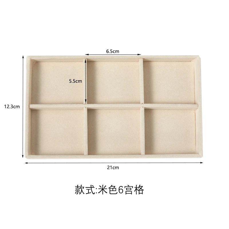 A rectangular beige plush velvet jewelry storage tray divided into six compartments.
