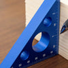 A blue precision aluminum triangle ruler showing both imperial and metric measurements on a wooden surface.