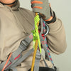 A person wearing a hoodie is adjusting an auxiliary rope knot for outdoor descent protection.
