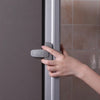 A hand is opening a gray refrigerator door using a silver safety cabinet lock.