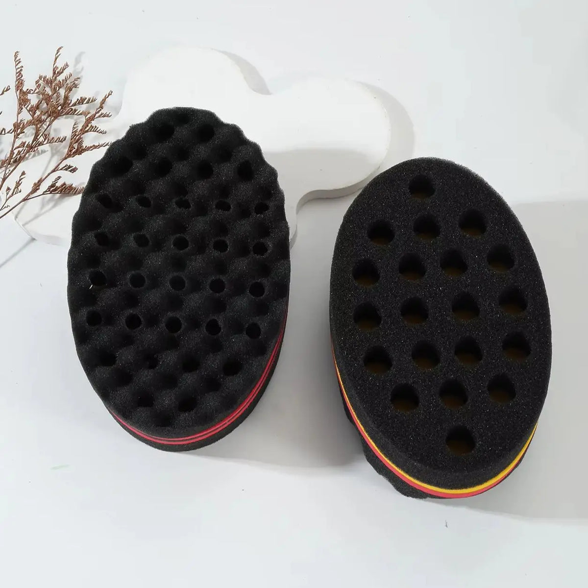 Un set de rouleaux en mousse noirs pour la coiffure des cheveux bouclés, montré à côté d'un support en plastique blanc.