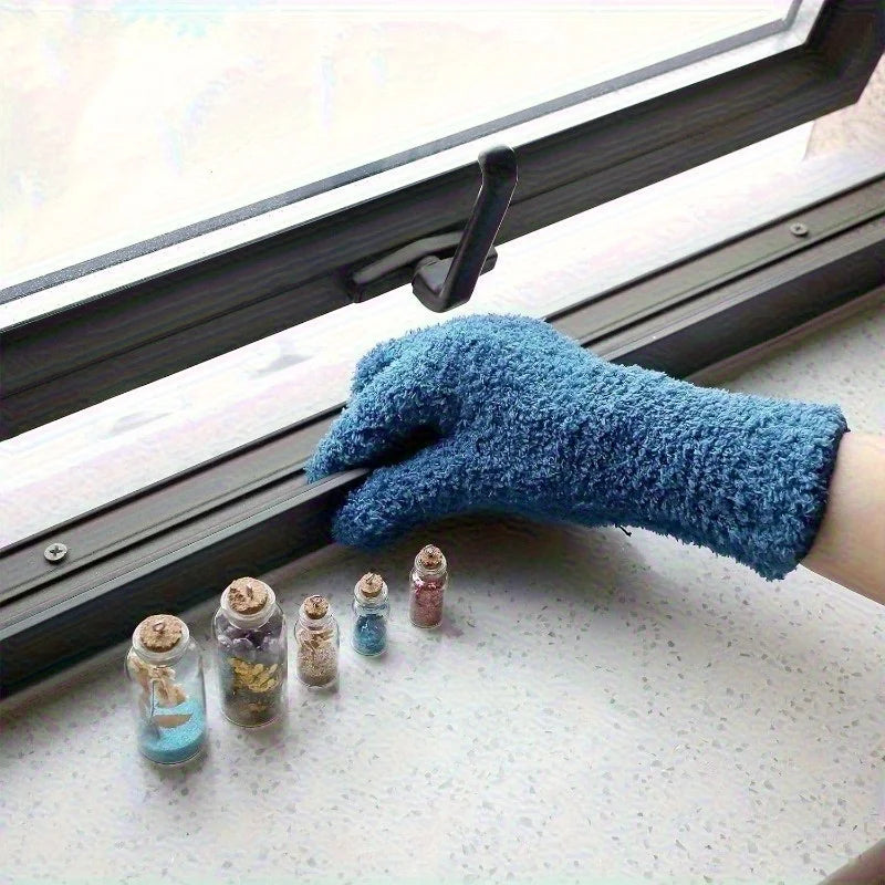 A hand wearing a blue microfiber dusting glove is positioned near a window frame with several small glass jars.