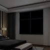 A modern bedroom interior featuring a large window covered with dark blackout film.