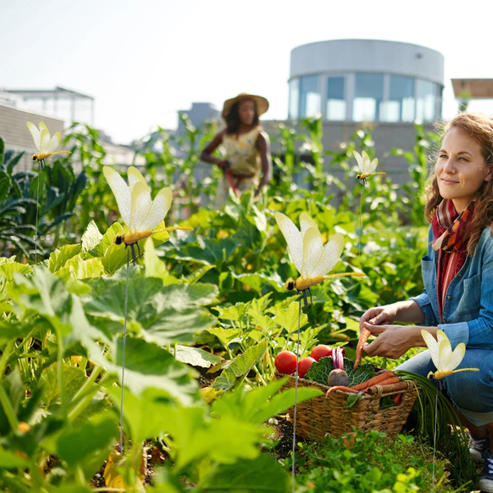 A woman is tending to a garden filled with green plants and white dragonflies.