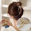 Elegant gold S-shaped metal hair clips with pearl accents used to style a woman's hair.