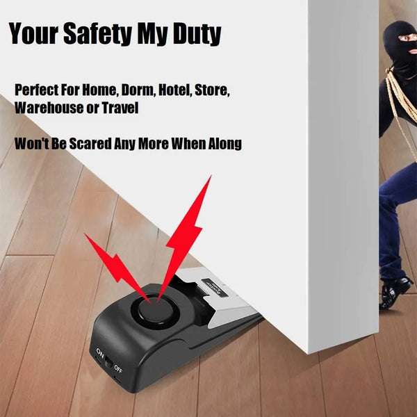 A black portable door stopper alarm wedge device is shown on a wooden floor.