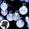 String lights with glowing orbs powered by solar panels against a dark background