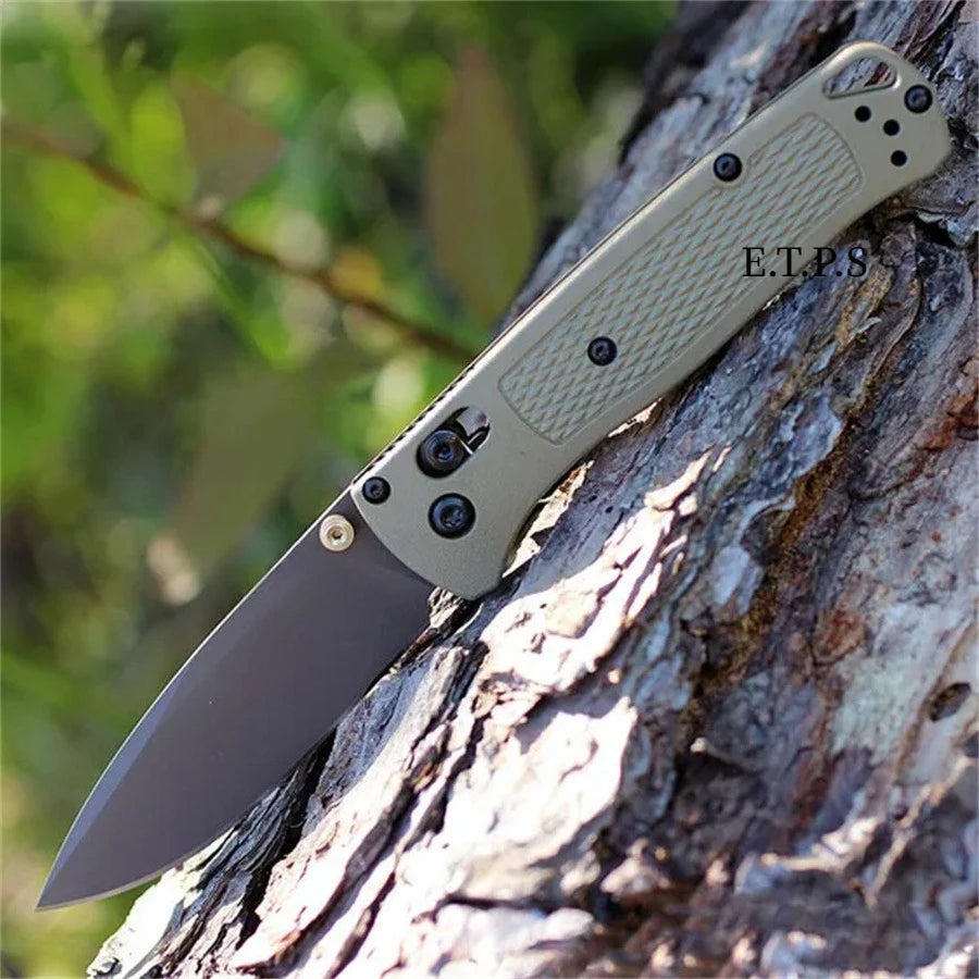 Un couteau de poche pliable (EDC) avec une poignée et une lame vert clair repose sur un tronc d'arbre.
