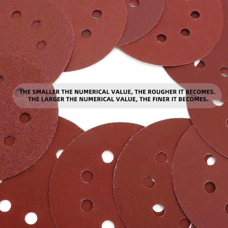 A collection of reddish-brown multi-grit hook and loop sanding discs, showing varying sizes.