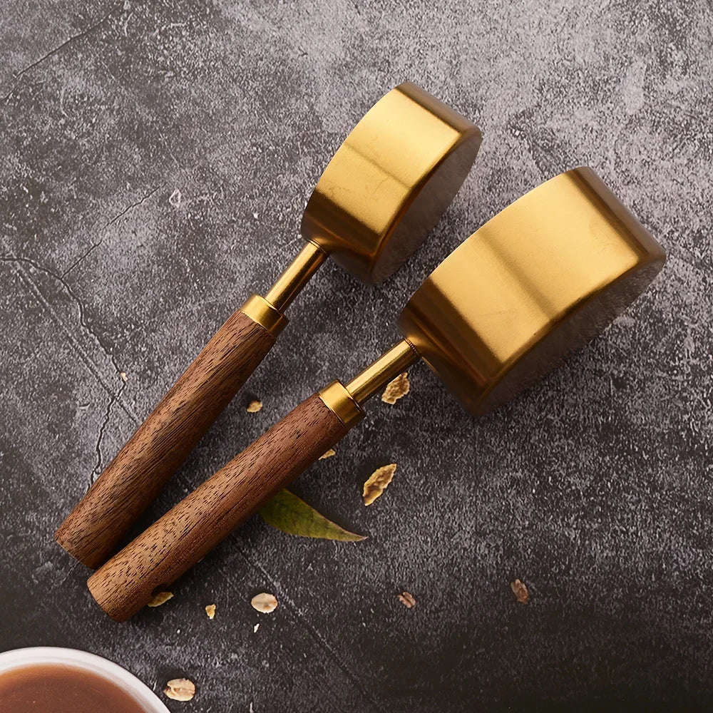 A pair of brass and wooden measuring spoons resting on a dark surface.