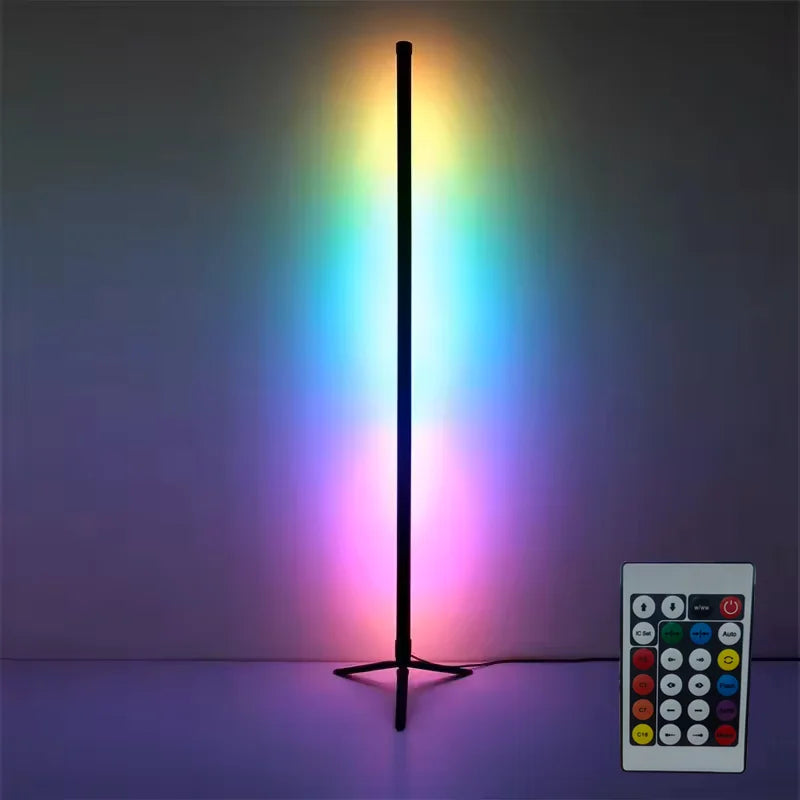 A tall black floor lamp emitting a rainbow spectrum of light on a purple surface, next to a remote control.