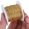 A hand holds a spool of gold-colored stainless steel beading wire for DIY jewelry making.