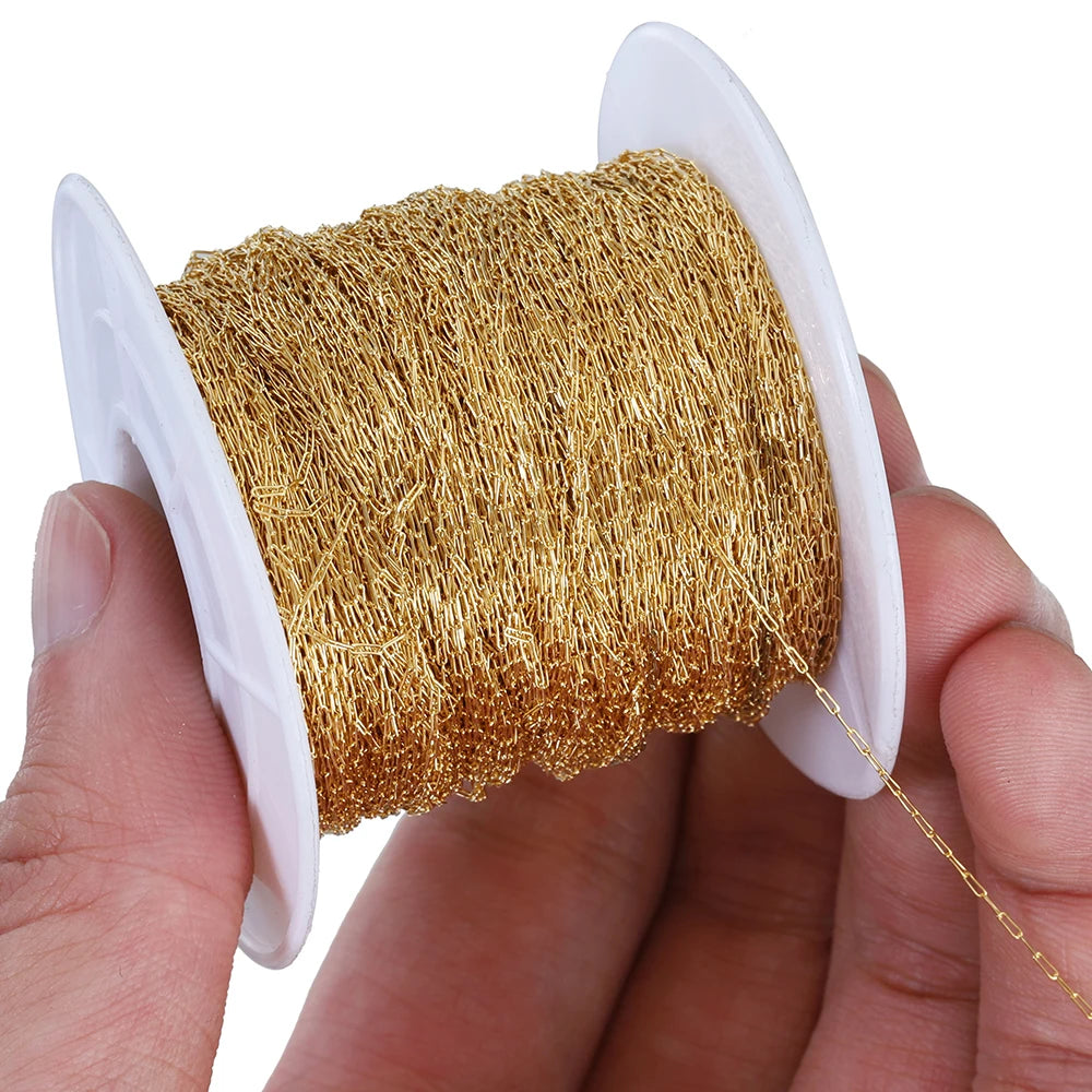 A hand holds a spool of gold-colored stainless steel beading wire for DIY jewelry making.