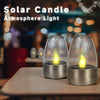 Dos luces de ambiente de velas solares brillando cálidamente sobre una mesa de madera.