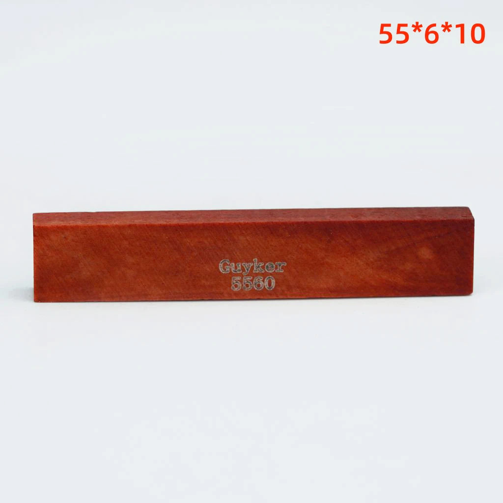 A rectangular piece of reddish-brown acoustic guitar bone bridge saddles labeled Guykor 5560