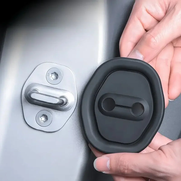 A hand is holding a black rubber door lock protection pad, showing its shape and texture against a silver door surface.