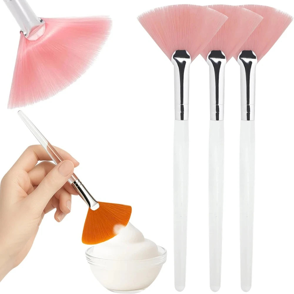 Un set de trois brosses pour masques faciaux en silicone rose, avec une main appliquant un masque orange dans un bol.