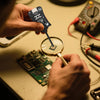 Una persona usa un probador de bobina de placa madre de precisión para inspeccionar un componente electrónico en una placa de