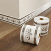 Bande décorative adhésive à appliquer avec motif de volute sur un parquet en bois.