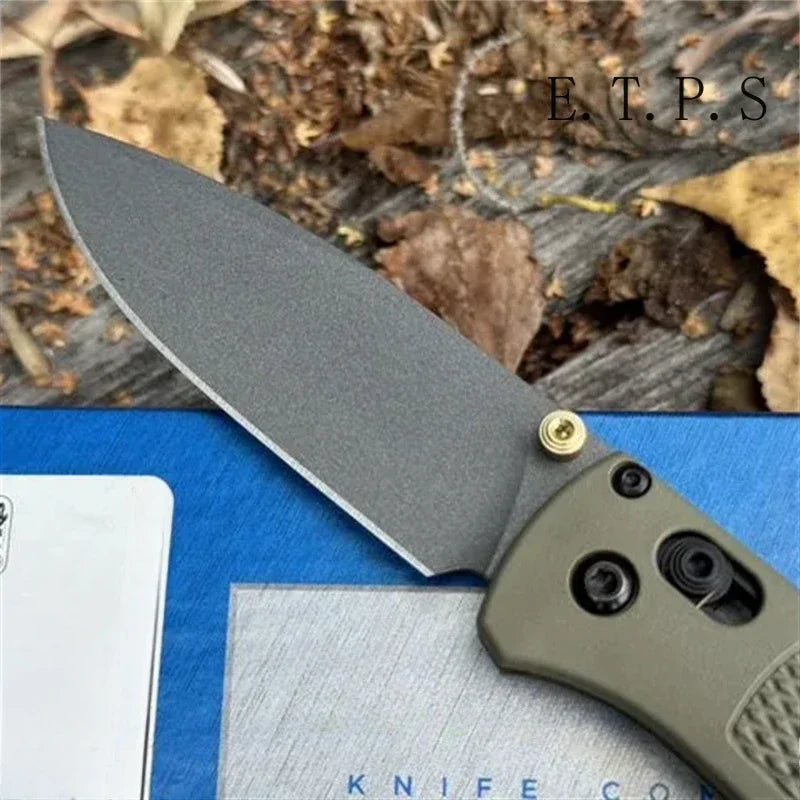 A gray folding EDC pocket knife with a visible blade and handle resting on a blue surface.