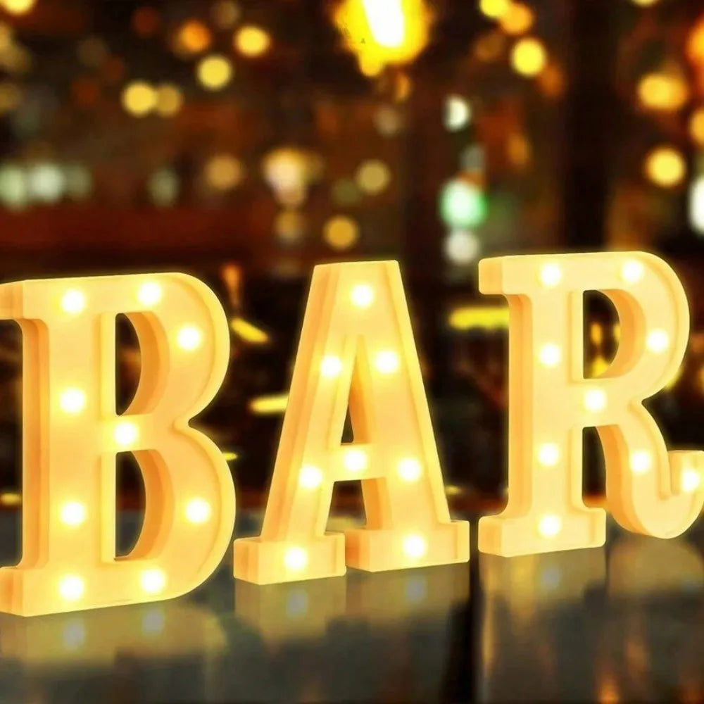 Luz nocturna de LED dorada con letras y números deletreando BAR en una superficie reflectante.