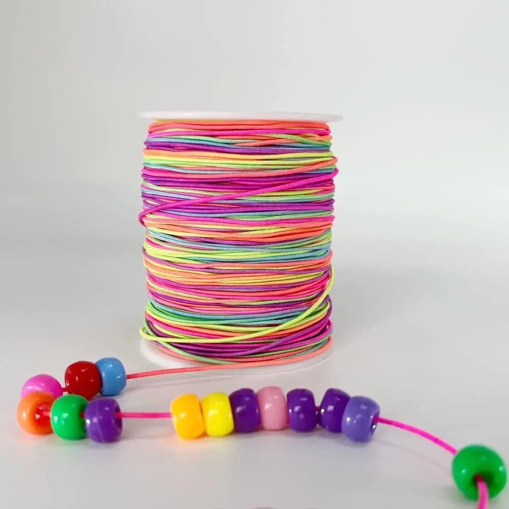 A spool of rainbow colored elastic beading cord with a loose end extending from the coil.
